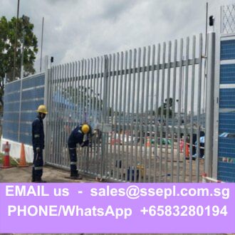 Two workers in hard hats install a tall gray metal fence at a construction site, with a purple banner showing contact info at the bottom (EMAIL sales@ssepl.com.sg, PHONE/WhatsApp +6583280194).