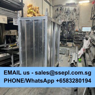 Industrial metal fabrication workshop with a large metal frame on a wheeled stand, surrounded by tools and equipment; a bright blue banner across the bottom shows contact details (email and phone) for inquiries.